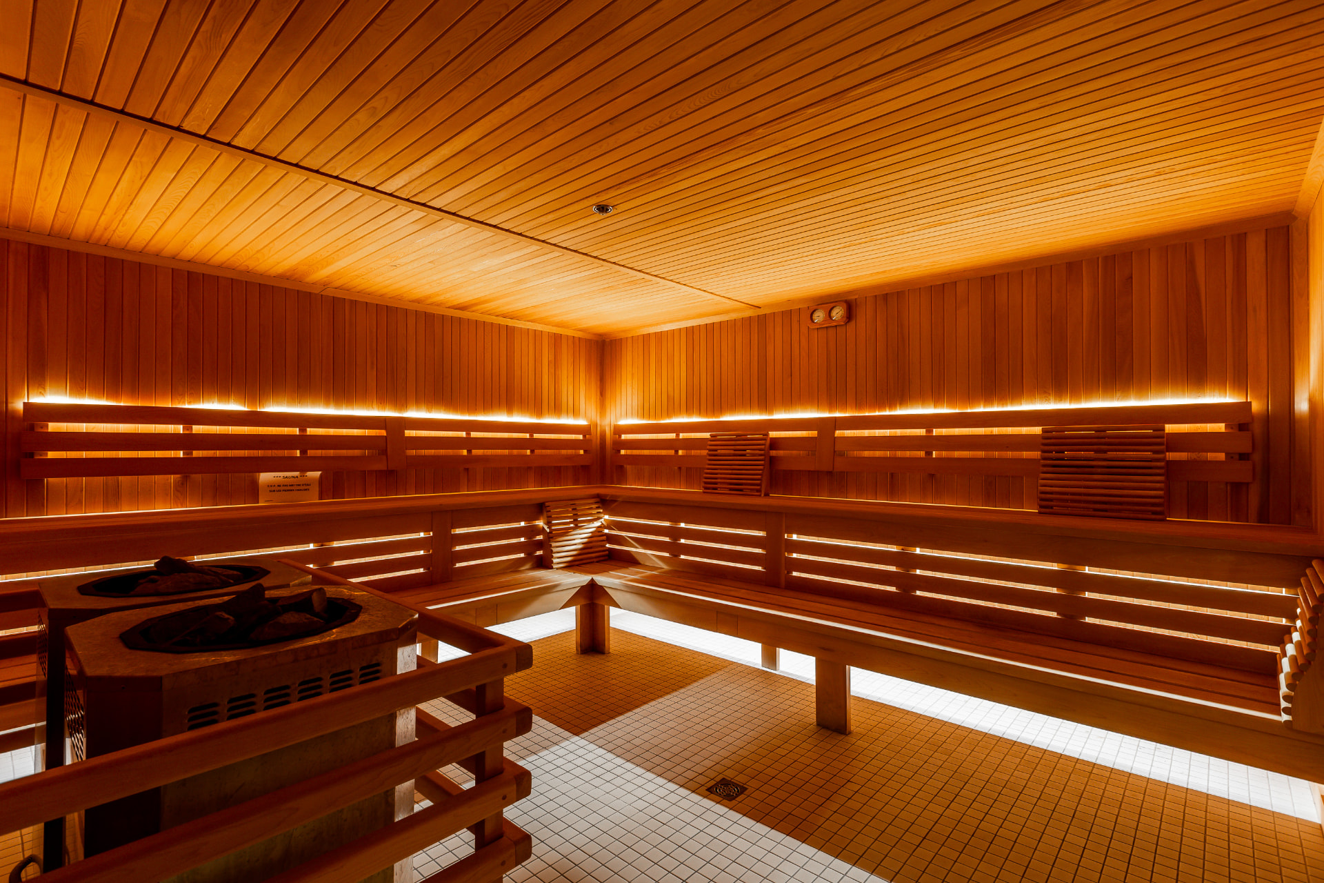 Sauna de bois avec bancs en étage, poêle à pierres et éclairage doux