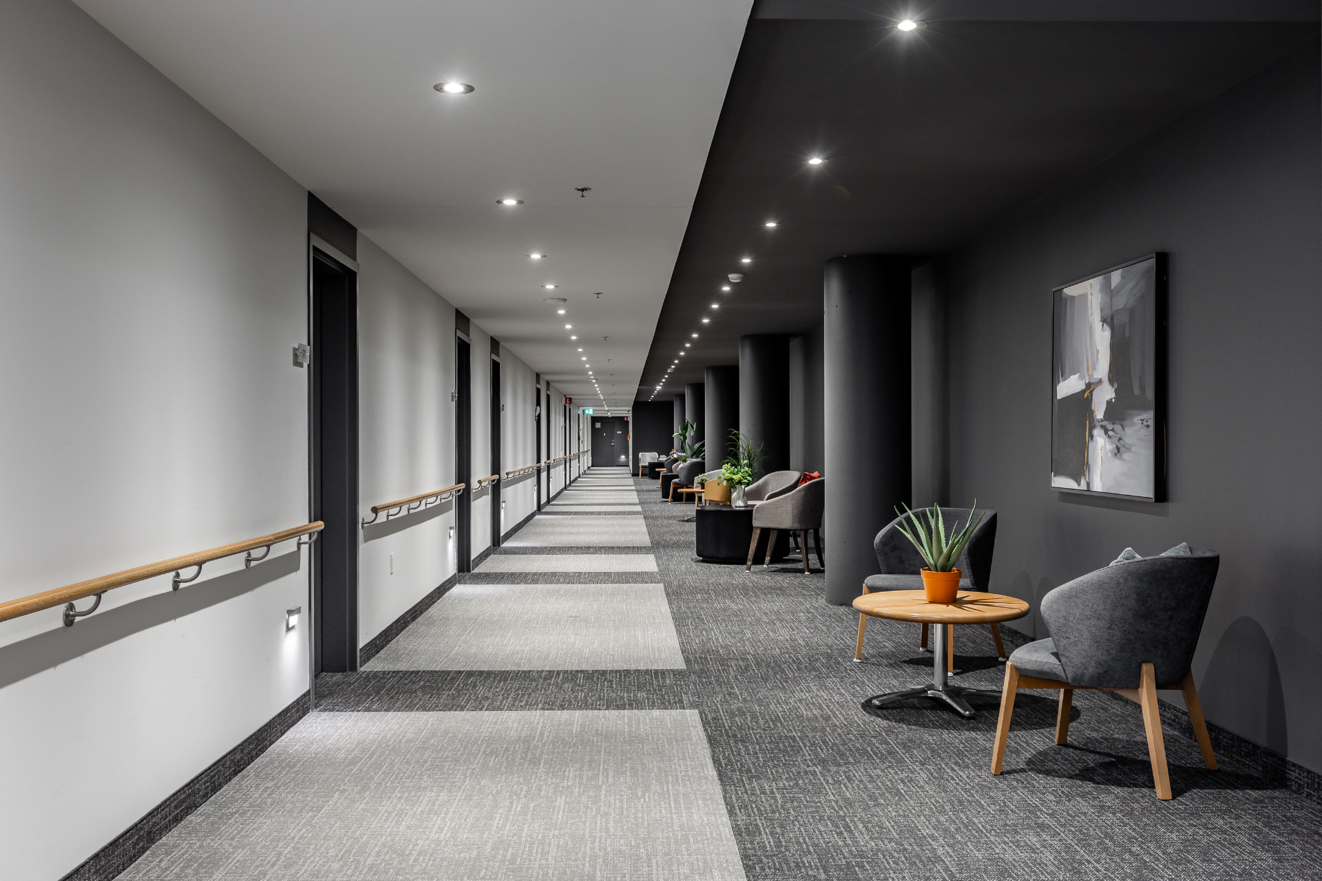 Couloir moderne aux murs gris et blancs avec coins repos et fauteuils