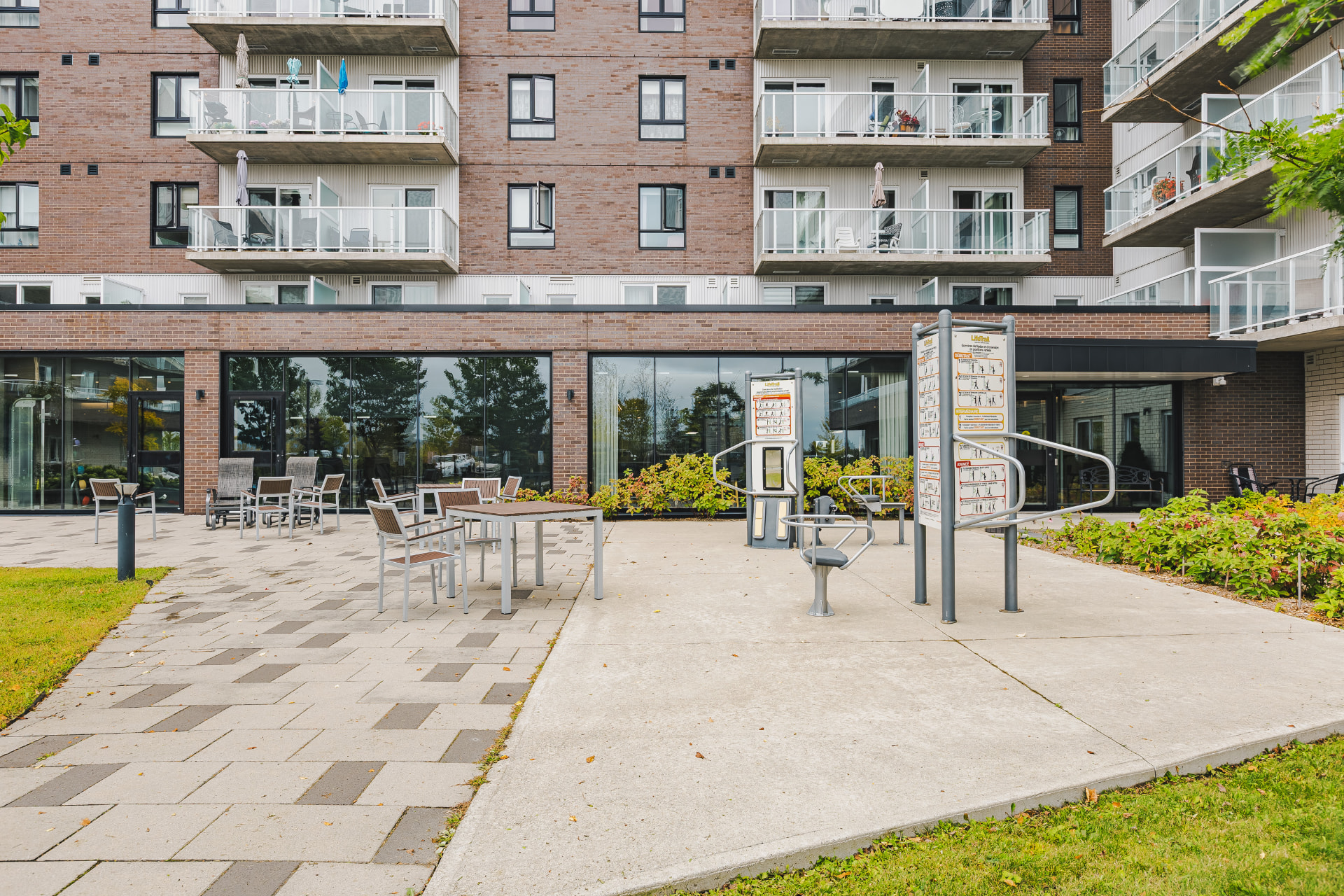 Cour extérieure aménagée avec tables de patio et appareils d'entraînement