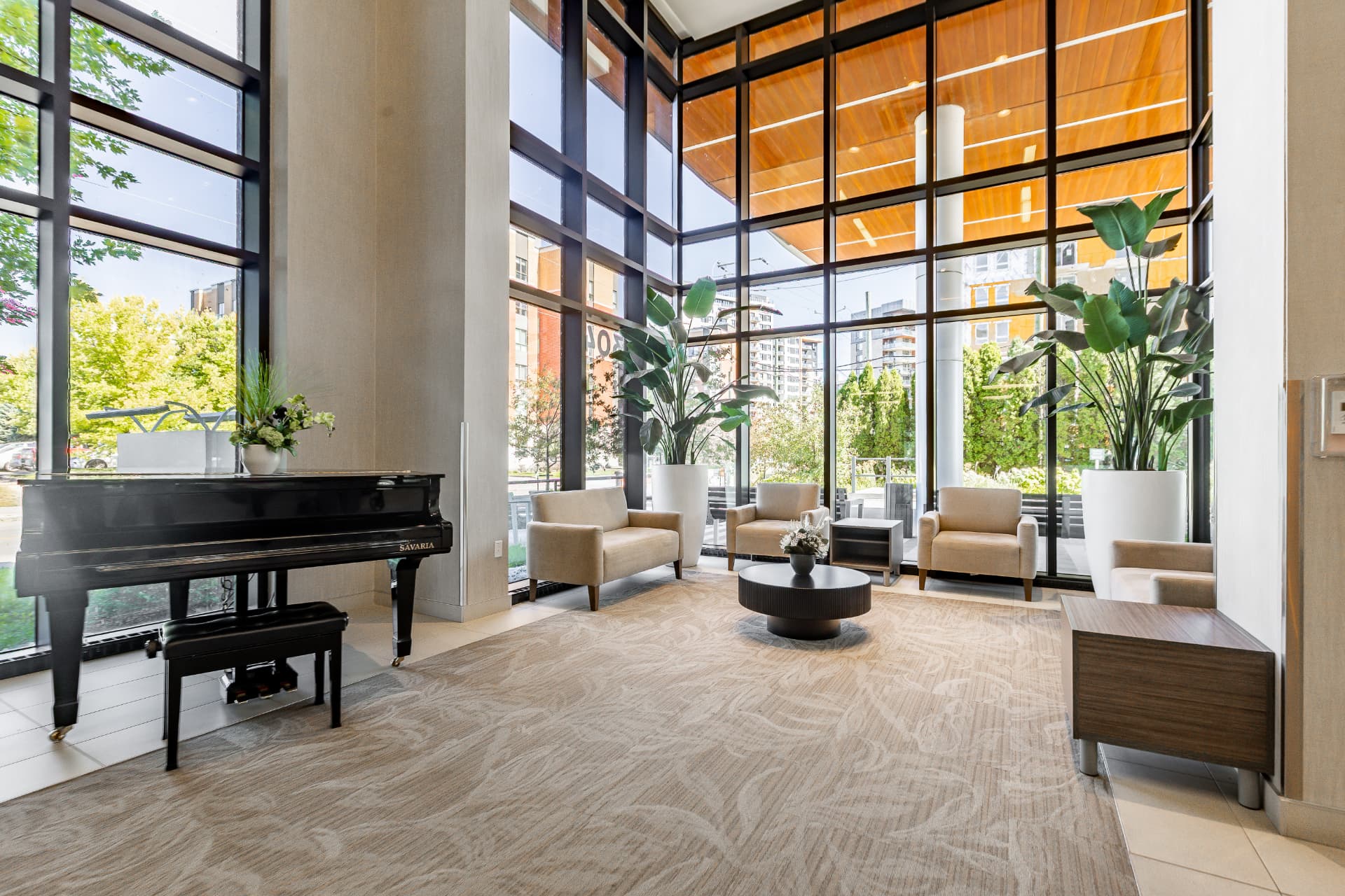 Grand hall vitré avec piano à queue, fauteuils confortables et plantes