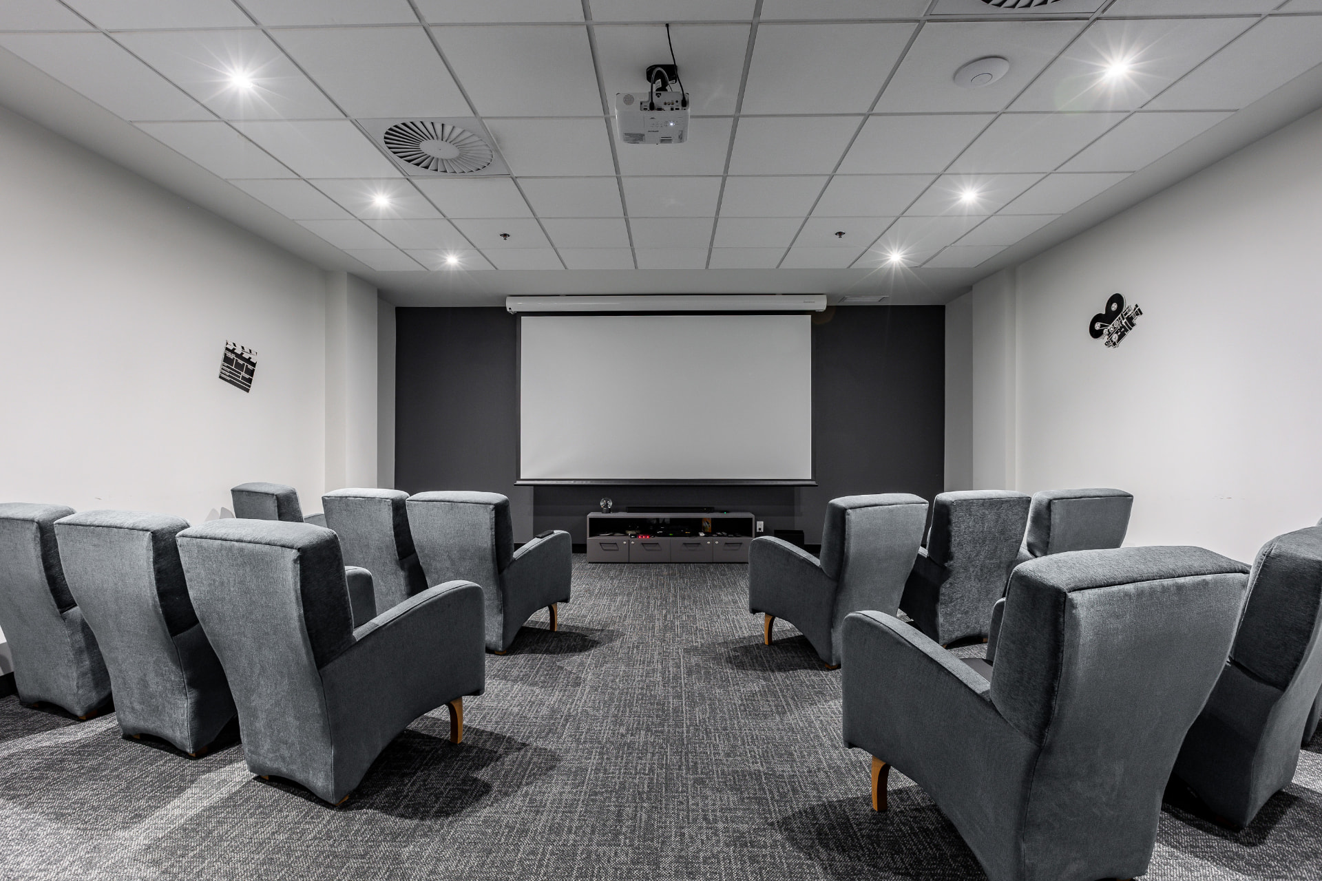 Salle de cinéma privée avec grand écran et fauteuils rembourrés