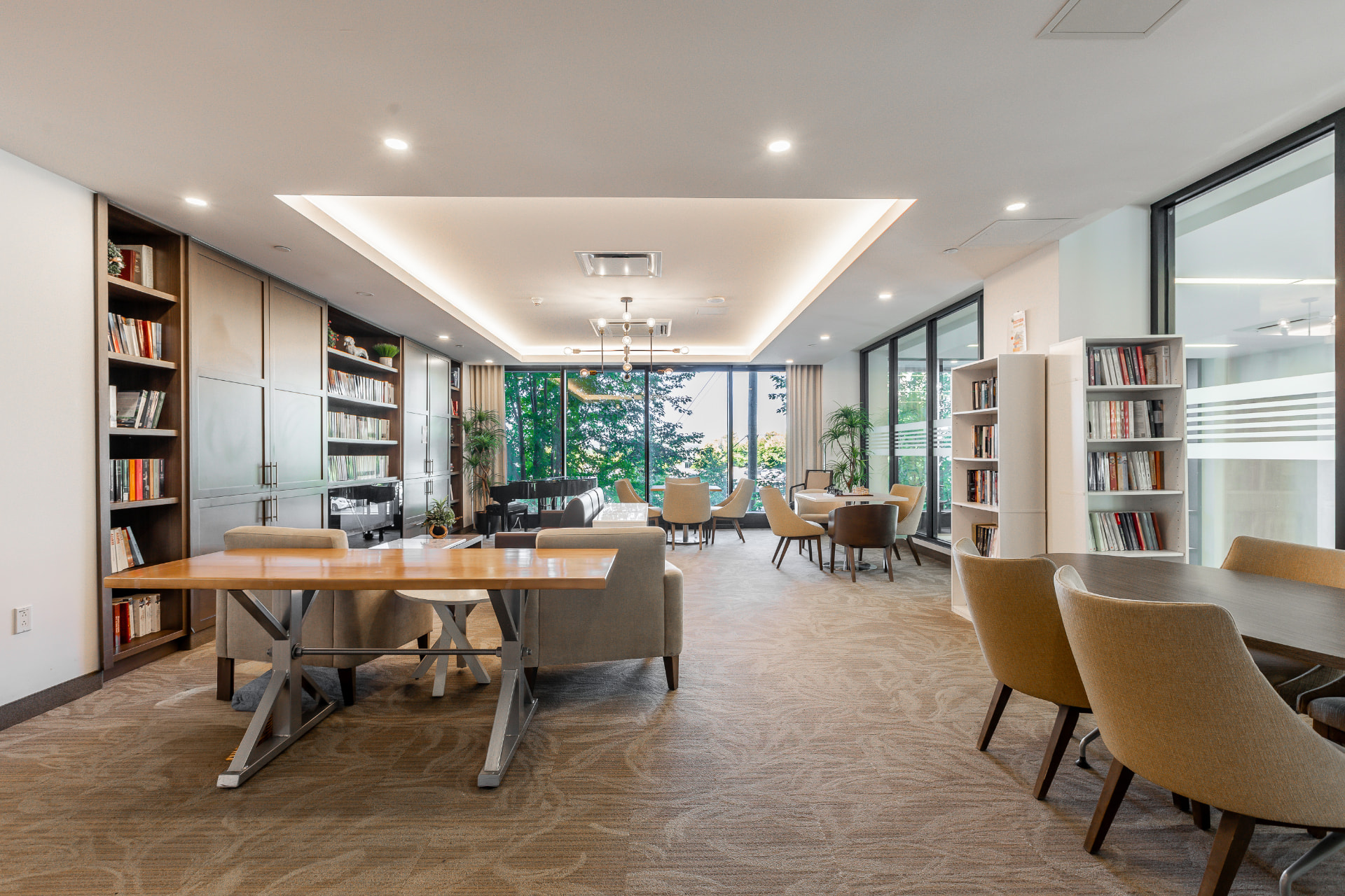 Bibliothèque avec grande table de bois, étagères et coin lecture