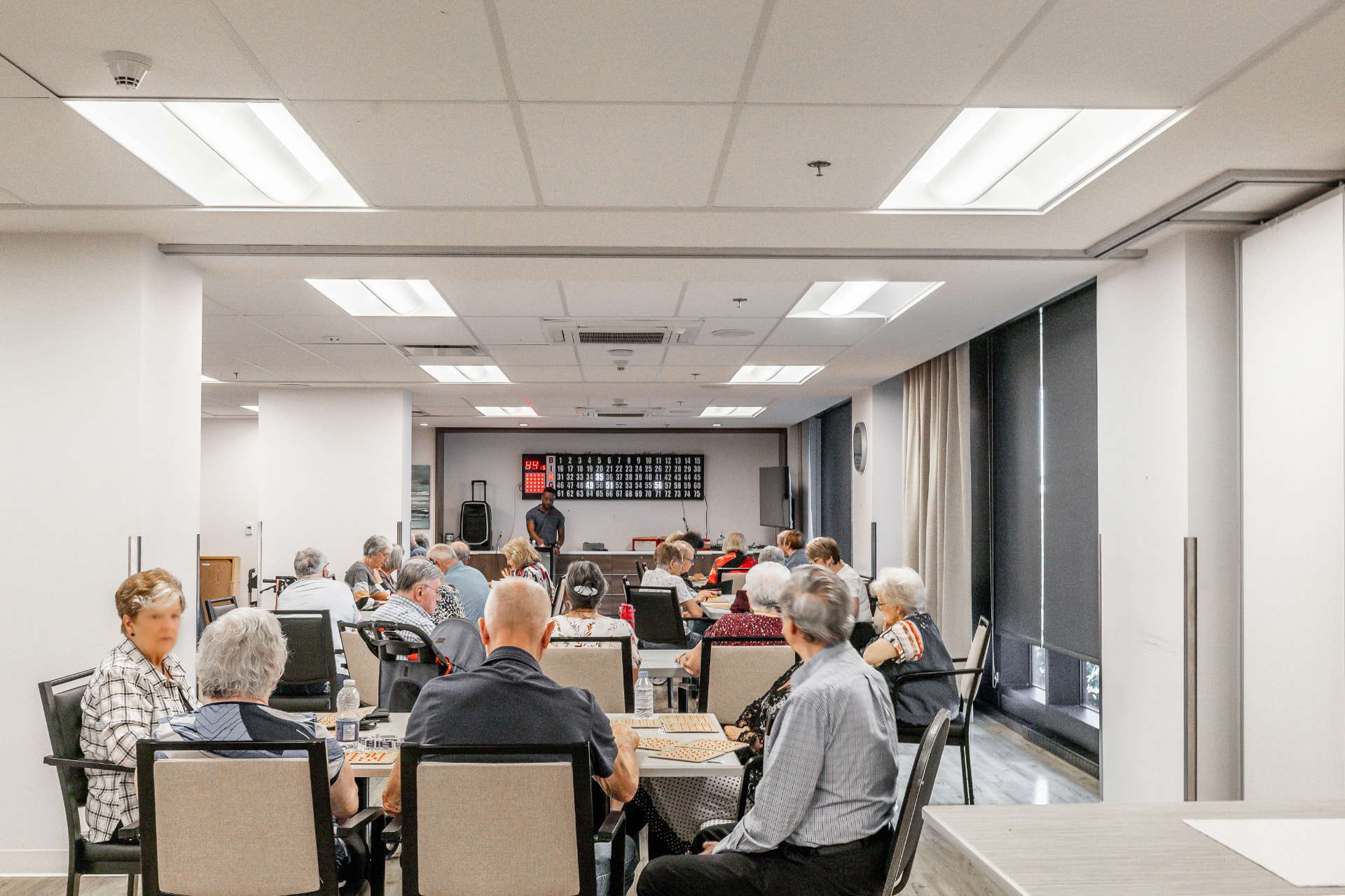Salle d'activités avec les résidents réunis autour des tables de jeu