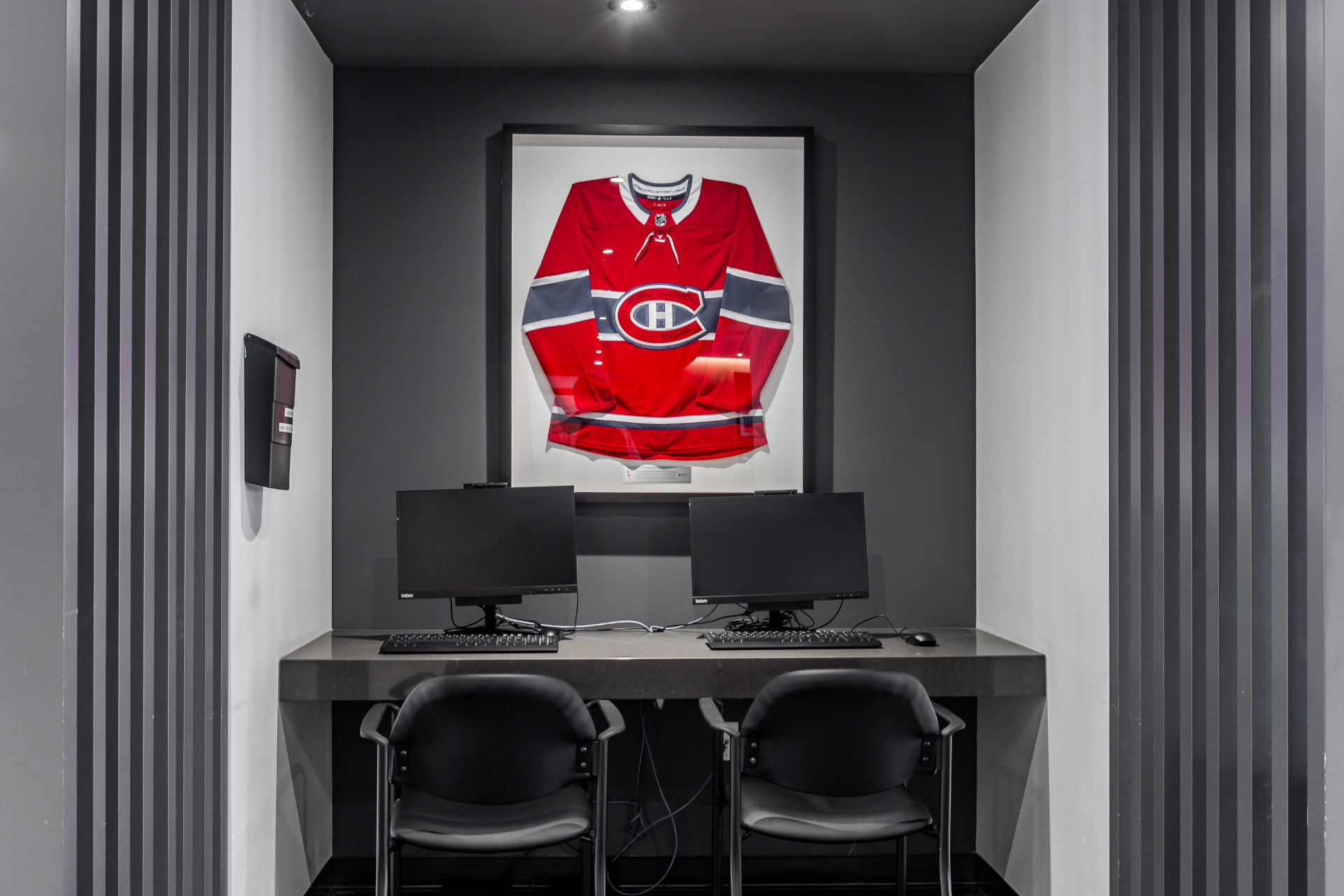 Espace informatique avec postes d'ordinateur et maillot de hockey encadré