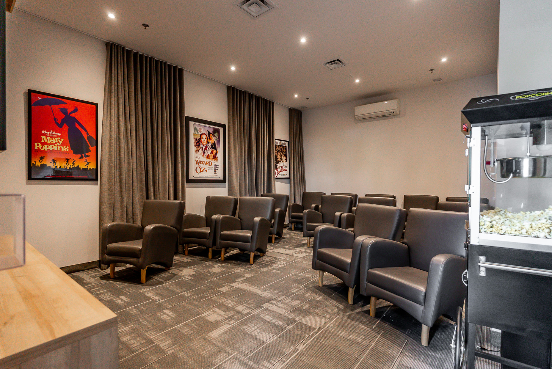Salle de cinéma avec fauteuils de cuir, machine à popcorn et affiches de classiques